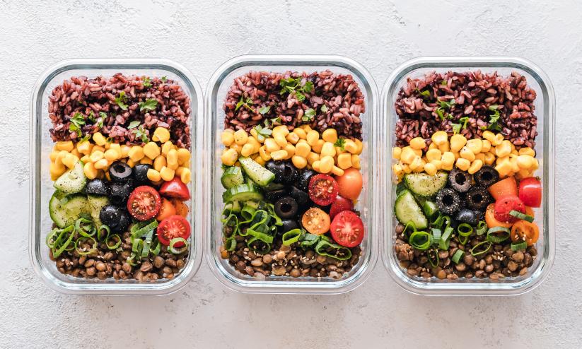 three glass tupperware boxes fillied with beans, pulses, fruit; they're all look brightly coloured, green, yellow, reds, brown.