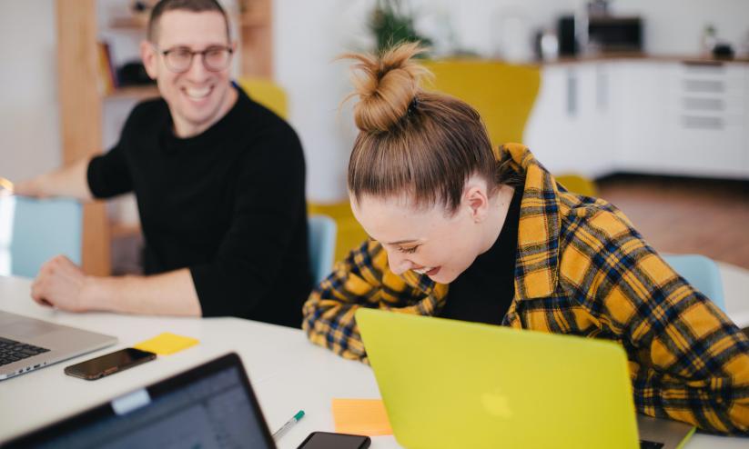 wellbeing in the workplace; man and woman laughing at their desks