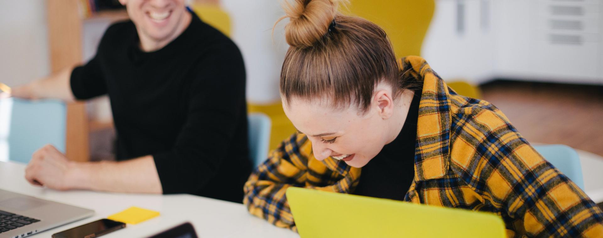 wellbeing in the workplace; man and woman laughing at their desks